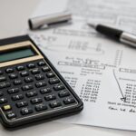 Close-up of financial documents with calculator and pen, ideal for business management themes.