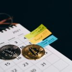 Bitcoin coins placed on a calendar with sticky notes for investment planning.