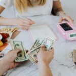 Two people handling cash and budgeting with a calculator and notebook at a table.