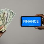 Image depicting currency and finance concept with hands holding cash and a smartphone.