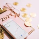 Close-up of a smartphone with crypto chart, bitcoin coins, and 2021 notepad.