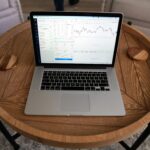 Close-up of a laptop displaying trading charts on a stylish wooden table, ideal for financial themes.