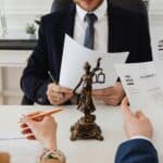 Legal professionals reviewing divorce documents in a law office with a Lady Justice statue.